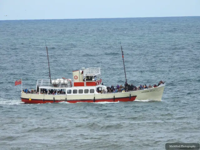 A passenger boat passes beneath the coastal cliffs at Bempton Cliffs.