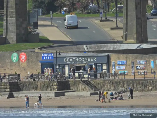 The Beachcomber café and the busy waterfront are seen from across the beach.