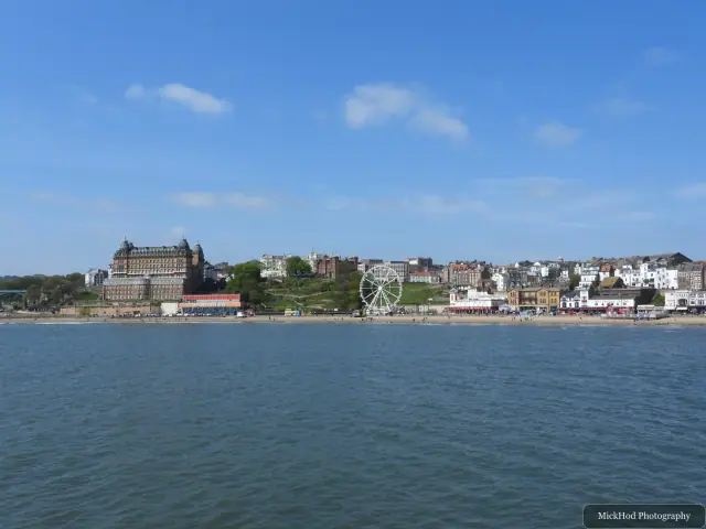 A broad view across South Bay shows the seafront buildings, beach and wheel beneath a clear sky.