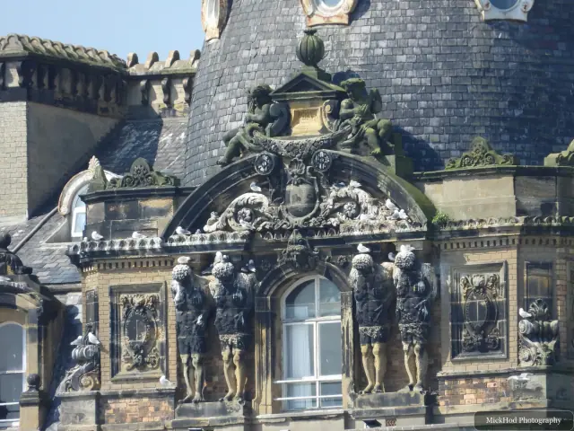 A detailed view of stone figures and decorative carving around a window on the Grand Hotel.