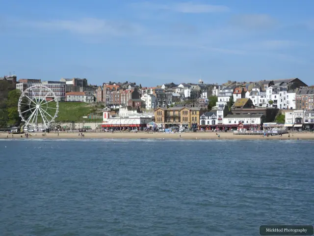 The curve of South Bay and its seafront buildings are seen across the calm water.