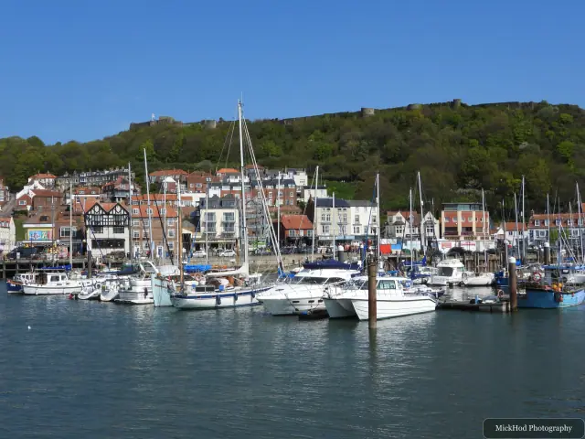 Sailing boats and yachts are moored in Scarborough Harbour beneath the hillside town.
