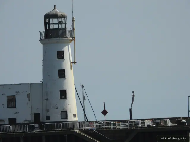A closer view of the lighthouse tower rises above the pier railings.